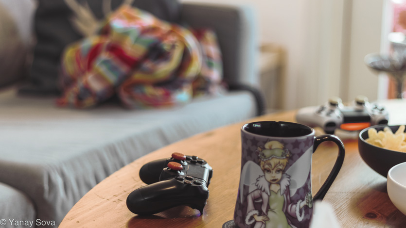 A couple of dualshock 4 controllers next to some coffee and snacks